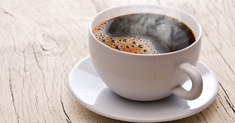 Cup of hot coffee on an old wooden table.